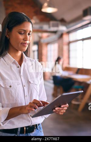 Young Businesswoman Using Digital Tablet Working In Modern Open Plan Office Stock Photo