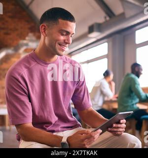 Young Businessman Using Digital Tablet Working In Modern Open Plan Office Stock Photo