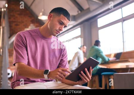 Young Businessman Using Digital Tablet Working In Modern Open Plan Office Stock Photo