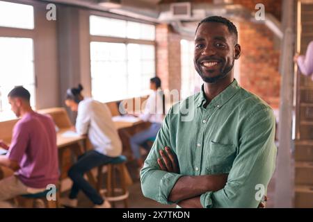 Portrait Of Smiling Businessman Working In Modern Office With Colleagues In Background Stock Photo
