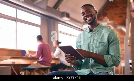 Portrait Of Businessman Using Digital Tablet Working In Modern Open Plan Office Stock Photo