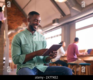 Businessman Using Digital Tablet Working In Modern Open Plan Office Stock Photo