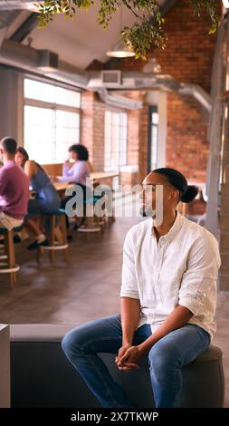 Smiling Businessman Working In Modern Office With Colleagues In Background Stock Photo