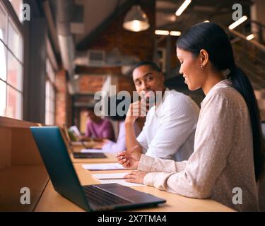 Male And Female Businesspeople Meeting In Office Discussing Documents With Colleagues In Background Stock Photo