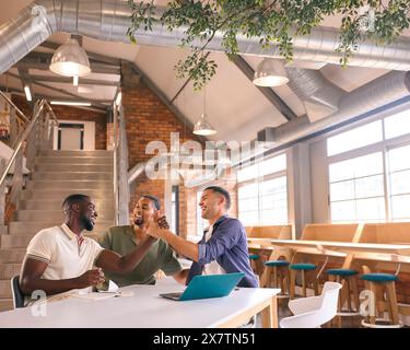 Businessmen Meeting In Modern Office Sitting Around Table Celebrating Shaking Hands Stock Photo