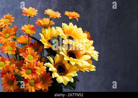 Bouquet yellow, orange flowers against dark concrete wall Stock Photo