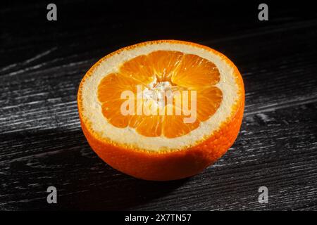 sliced calabrian oval blond oranges on black wood background Stock Photo