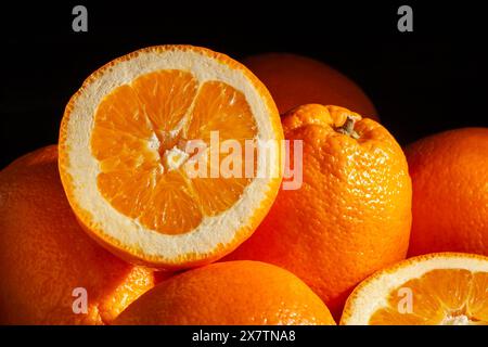 sliced calabrian oval blond oranges on black background Stock Photo