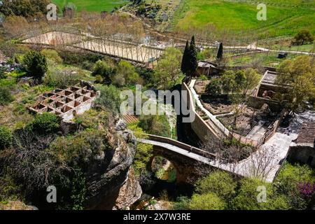 Tourists stand on the ancient Arab Bridge above the Roman Baths, along the old city wall in Ronda, Malaga Province, Spain. Stock Photo