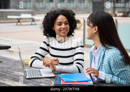 Two multiethnic students with books and laptop at University campus Stock Photo