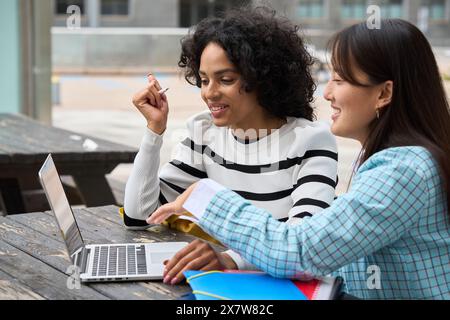 Two women sitting at a table with a laptop open Stock Photo