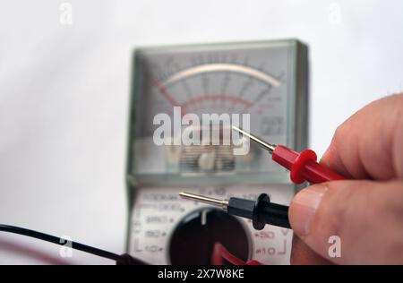 Electrician working with analog multimeter. Focused on probes. Stock Photo