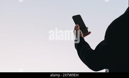 Male holding a smartphone, reading a text on the touchscreen. He uses a mobile app for social media, connected to a network. Stock Photo