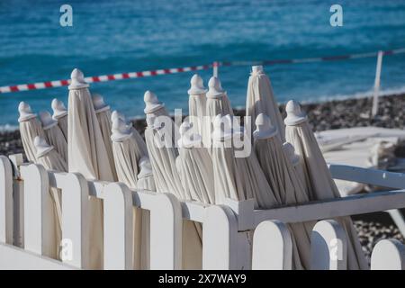 Closed sun umbrellas on the beach in the morning, at the end of the season Stock Photo