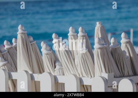 Closed sun umbrellas on the beach in the morning, at the end of the season Stock Photo