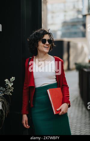 Smiling businesswoman with sunglasses holding a notebook outdoors Stock Photo