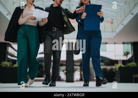 Group of three professionals walking indoors discussing business documents Stock Photo