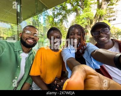 Four black student friends take selfie take break from studying while sit outside university library Stock Photo