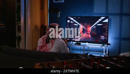 Middle Eastern gamer feeling gutted after losing singleplayer action videogame level, being outsmarted by enemies. Muslim man at home frustrated after seeing game over screen Stock Photo