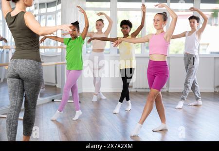 Teen girl practicing ballet movements at group class Stock Photo