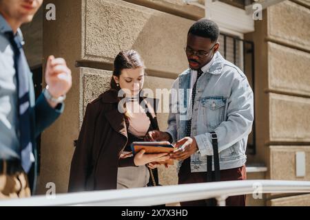 Business professionals discussing project outdoors, focused on digital tablet Stock Photo