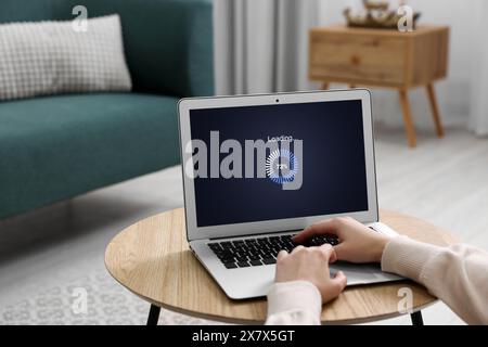 Loading screen displaying progress. Woman working on laptop at table indoors, closeup Stock Photo