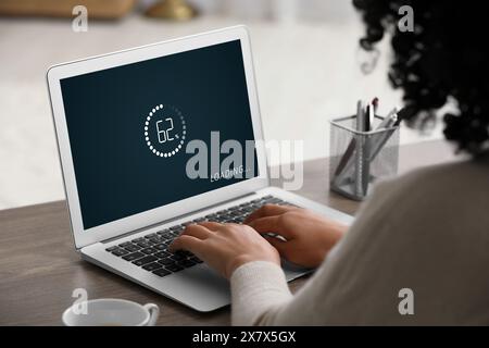 Loading screen displaying progress. Woman working on laptop at table indoors, closeup Stock Photo