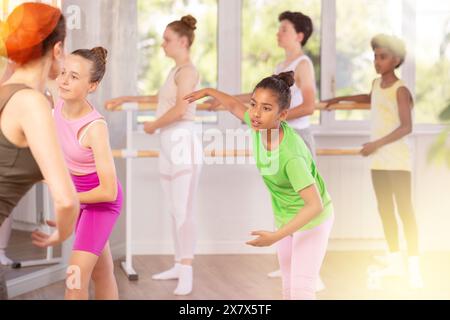 African American preteen girl practicing ballet movements during group class Stock Photo