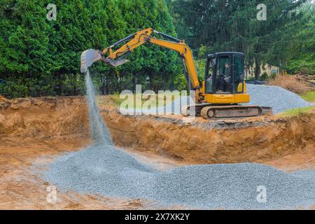 To serve as foundation for a concrete structure, excavators fill irregularities in excavations with granite rubble base Stock Photo