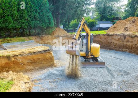 An excavator fills irregularities in excavations with granite rubble base for which concrete foundation in construction site Stock Photo