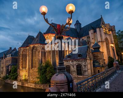 Gothic cathedral at dusk with illuminated streetlamp in the foreground, situated at the water canal, there is a quiet and historical atmosphere, histo Stock Photo
