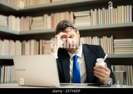 Tired man having a terrible headache. Exhausted man feeling unhealthy, upset about headache illness. Stressed middle-aged man having headache Stock Photo