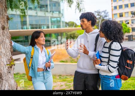 Three multi-ethnic friends talking leaning on a tree in the university Stock Photo
