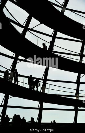 Dark people walking backlight in the shadow of an office ramp. Black people on modern building staircase. Business people walking in a workplace Stock Photo