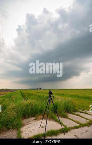 A photo camera with lightning trigger is set up near a majestic supercell thunderstorm during a storm chase on the Great Plains Stock Photo