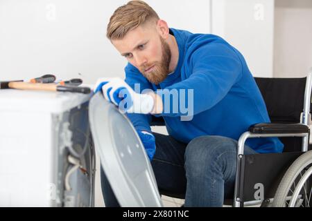 manual worker in wheelchair working with metal pipes Stock Photo