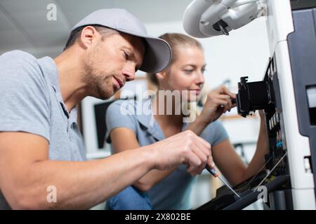 male and female technicians working on photocopier Stock Photo