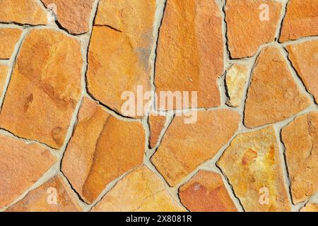 The texture and background of the golden sandstone wall are made in the form of rough, uniform cobblestone masonry. Stock Photo