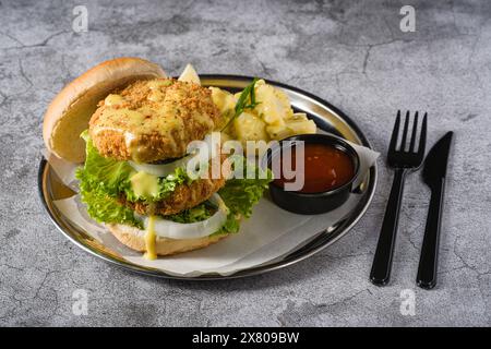 Double fish burger with potato salad on a metal plate Stock Photo