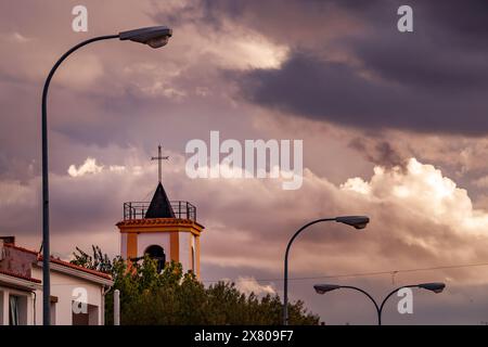 Ruidera's bell tower with street lamps at sunset. Stock Photo