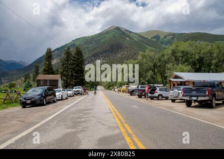 Cars and trucks parked along Highway 82, bicyclists on road, in Twin Lakes, Colorado, the eastern gateway to Independence Pass, USA. Stock Photo