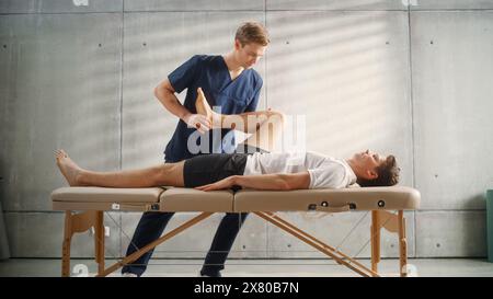 Young Male Athlete Undergoing Physiotherapy, Professional Sport Masseur Treating Light Muscle or Joint Injury. Musculoskeletal Pain Therapy and Rehabilitation Clinic Concept. Stock Photo