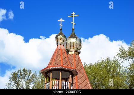 The church building features two gold crosses on the steeple, reaching up into the sky as a prominent finial atop the roof Stock Photo