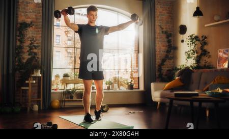 Fit Athletic Strong Young Man Doing Core Strengthening Workout with Dumbbells During Morning Session at Home in Sunny Apartment. Concept of Healthy Lifestyle and Fitness. Stock Photo