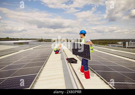 Electricians Installing And Maintaining Solar Panels On Roof Stock Photo