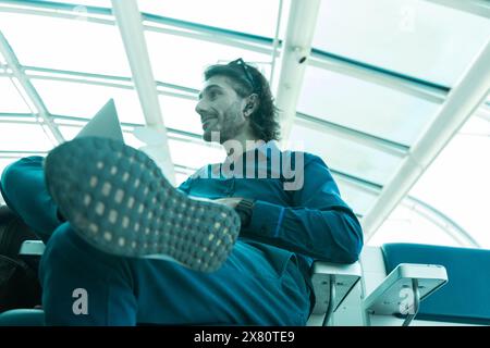 Portrait of one young latin American Caucasian man working on a computer laptop inside and airport. Stock Photo