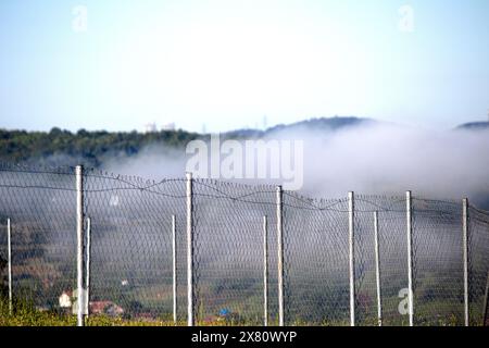 Stainless steel fence wire in front of foggy background. Garden wires are networks woven with steel cables. Terrace fence or railing. Safety equipment Stock Photo