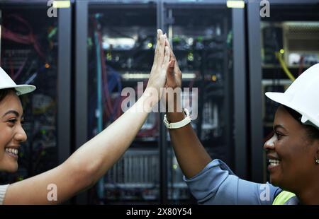Technician, teamwork and people high five for success in server room or programming maintenance. Happy, engineer and achievement in datacenter with Stock Photo