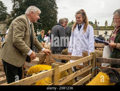Judge inspecting sheep while their owner, dressed in a white coat, looks on at Masham Sheep Fair. North Yorkshire, UK Stock Photo