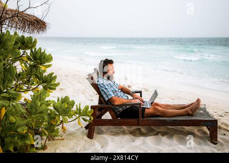 man working on laptop on exotic beach Stock Photo